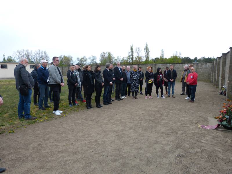 Gruppe von Menschen versammelt an einer Gedenkstätte.