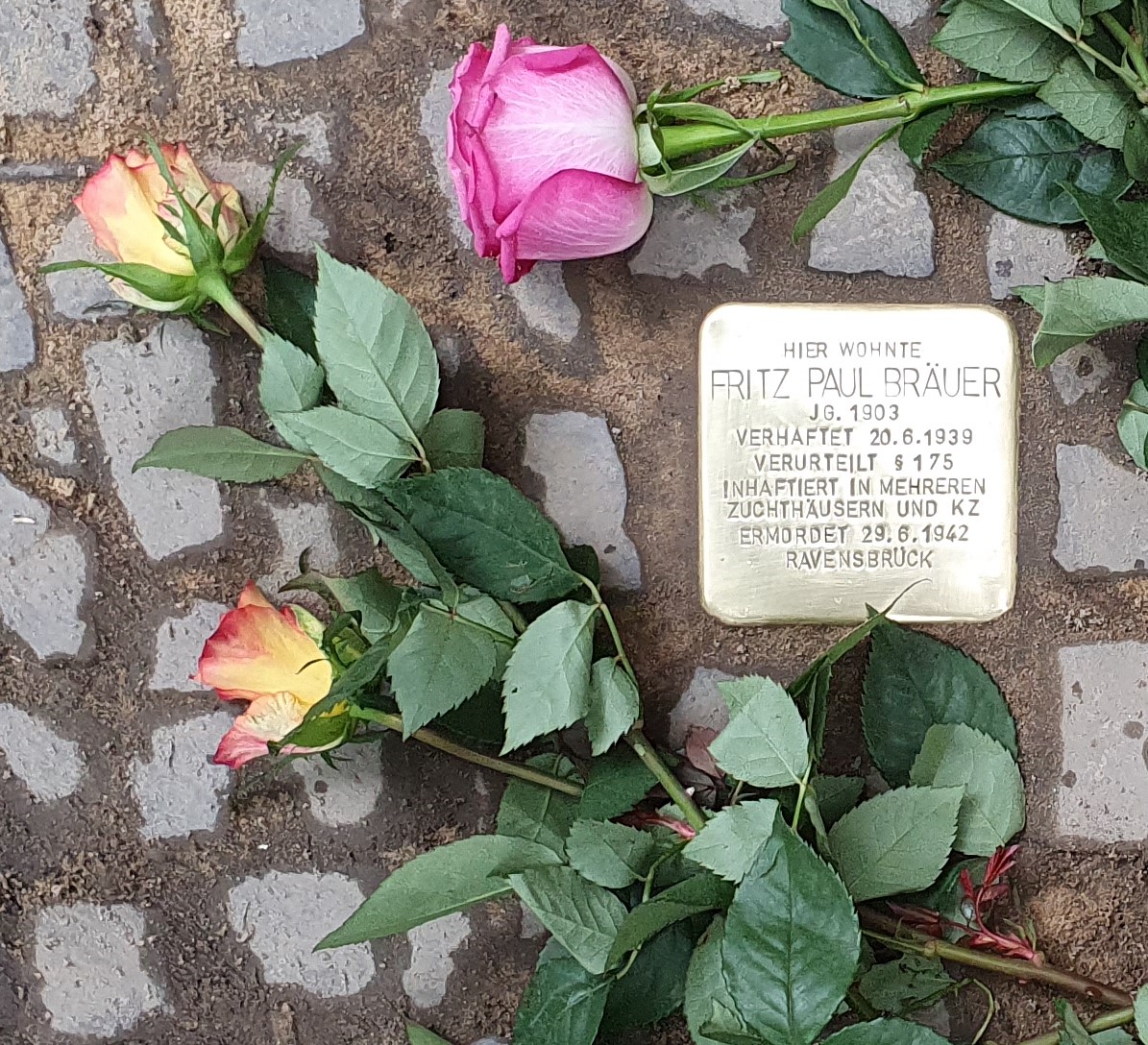 Stolperstein für Fritz Paul Räuer mit Rosen auf Kopfsteinpflaster.