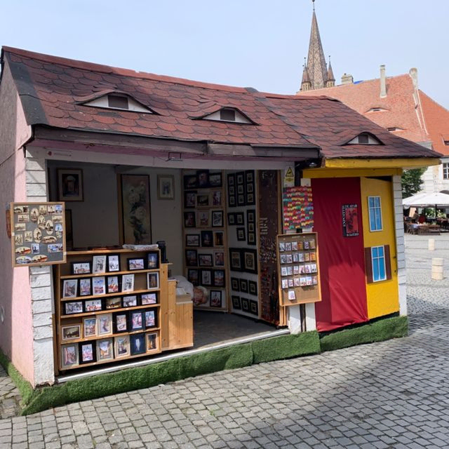 Kleiner, ungewöhnlicher Laden mit Büchern und augenähnlichen Fenstern.